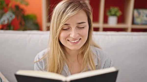 Young Blonde Woman Reading Book Sitting Sofa Home — Stock fotografie