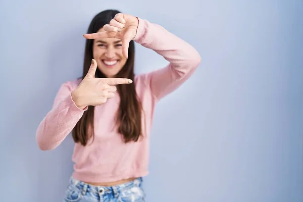 Young Brunette Woman Standing Blue Background Smiling Making Frame Hands — Fotografia de Stock