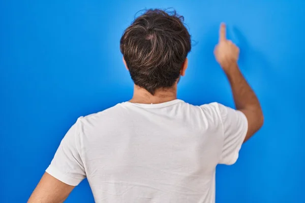 Hispanic Young Man Standing Blue Background Posing Backwards Pointing Ahead — Foto Stock