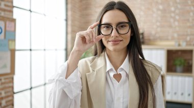 Genç, güzel, İspanyol bir iş kadını ofiste kendinden emin gülümsüyor.