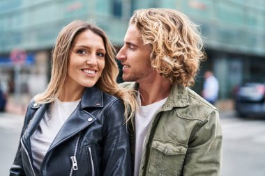 Erkek ve kadın bir arada durarak gülümsüyor.