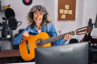 Orta yaşlı bir kadın müzik stüdyosunda klasik gitar çalıyor. Gururla bağırıyor, zaferi ve başarıyı kutluyor. 