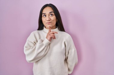 Pembe arka planda duran genç Güney Asyalı kadın parmak çenesinde şüpheye yoğunlaşmıştı. 
