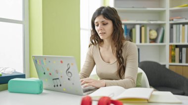 Kütüphanede dizüstü bilgisayar kullanan güzel İspanyol bir kız öğrenci.