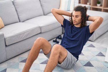 Young hispanic man training abs exercise at home