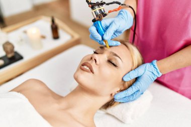 Young caucasian woman lying on table having microblading treatment at beauty salon clipart