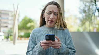 Sokakta akıllı telefon kullanan genç sarışın kadın.