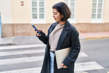 Sokakta dizüstü bilgisayar kullanan genç bir kadın.