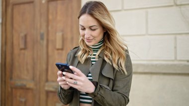 Sokakta akıllı telefon kullanan güzel bir İspanyol kadın.