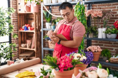 Çiçekçide deftere yazan genç Çinli bir çiçekçi.