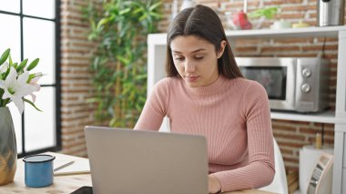 Yemek odasındaki masada dizüstü bilgisayar kullanan güzel İspanyol kadın.