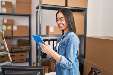 Genç, güzel, İspanyol bir kadın. İş kadını. Ofiste dokunmatik ped kullanıyor.