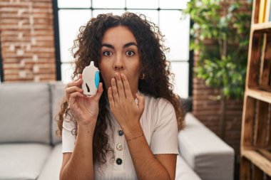 Genç İspanyol kadın glikoz ölçer kullanıyor. Ağzını eliyle kapatıyor. Şok geçiriyor ve hata yapmaktan korkuyor. şaşırmış ifade 