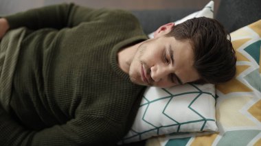 Genç İspanyol adam kanepede uzanıp evde uyuyor.