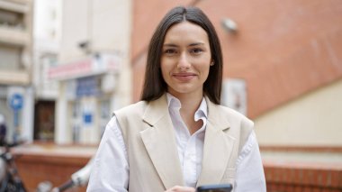 Sokakta gülümseyen akıllı telefon kullanan genç, güzel İspanyol kadın.