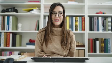 Güzel İspanyol bayan öğrenci kütüphane üniversitesinde video araması yaptığından emin bir şekilde gülümsüyor.