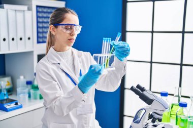 Laboratuvarda test tüpleri tutan genç bilim kadını.