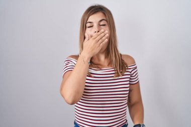 Tecrit edilmiş arka planda duran genç İspanyol kadın ağzıyla ağzını kapatmaktan sıkılmış. Huzursuz ve uykulu.. 