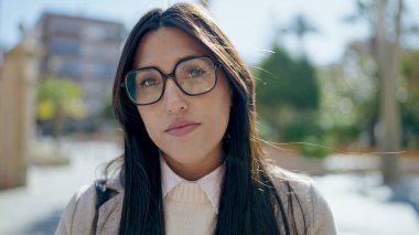 Parkta ciddi bir ifadeyle duran genç, güzel İspanyol kadın.