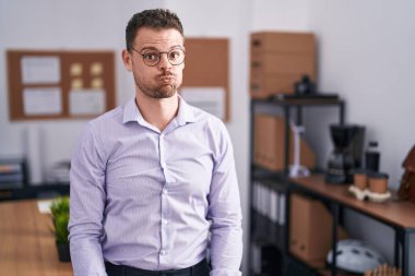 Ofisteki genç İspanyol adam komik suratıyla yanaklarını şişiriyor. Havayla şişmiş ağız, çılgın bir ifade.. 