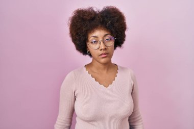 Genç Afrikalı Amerikalı kadın pembe arka planda duruyor. Uykulu ve yorgun görünüyor. Yorgun ve akşamdan kalma, tembel bakışlar.. 