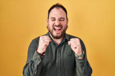 Ayrıca sarı arka planda dikilen sakallı, kolları havada ve gözleri kapalı zaferi kutlayan İspanyol bir adam. Kazanan konsept. 