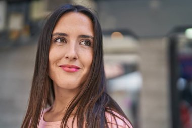 Young beautiful hispanic woman smiling confident looking to the side at street