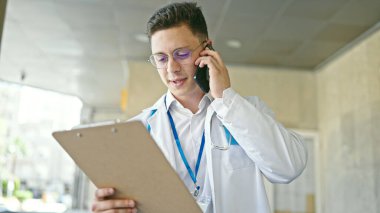 Genç İspanyol doktor hastanede akıllı telefon okuyarak konuşuyor.