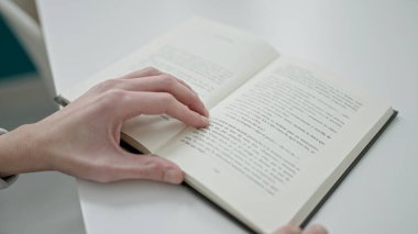 Genç İspanyol adam üniversite sınıfında oturmuş kitap okuyor.