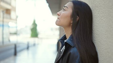 Young beautiful hispanic woman looking to the side with serious expression at street