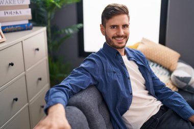 Evdeki koltukta kendinden emin gülümseyen beyaz bir genç.