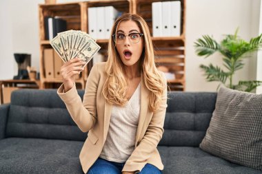 Terapi ofisinde çalışan genç sarışın kadın elinde parayla korkmuş ve ağzı açık bir şekilde şaşırmış, inançsız bir yüz ifadesi vardı. 