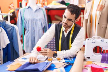 Genç İspanyol terzi, elinde dikiş iğnesiyle masada oturuyor.
