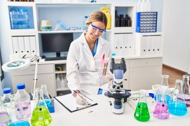 Genç İspanyol kadın bilim adamı, laboratuardaki test tüplerini tutan belgelere yazı yazmış.