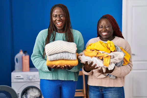 Dos Mujeres Africanas Sosteniendo Ropa Doblada Después Planchar Guiño Mirando — Foto de Stock
