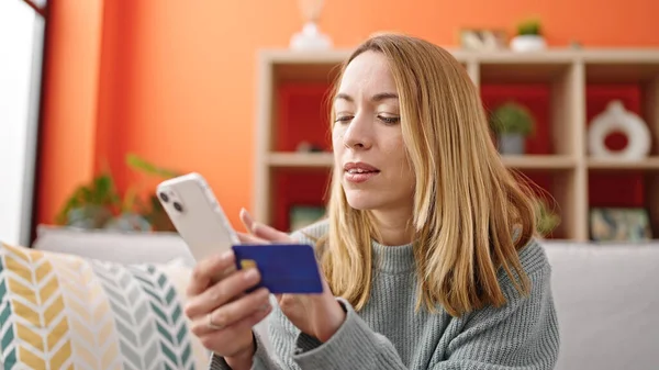 Молода Блондинка Купує Смартфоном Кредитною Карткою Сидячи Дивані Вдома — стокове фото
