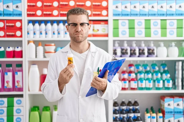 Young Caucasian Man Working Pharmacy Drugstore Holding Pills Skeptic Nervous —  Fotos de Stock