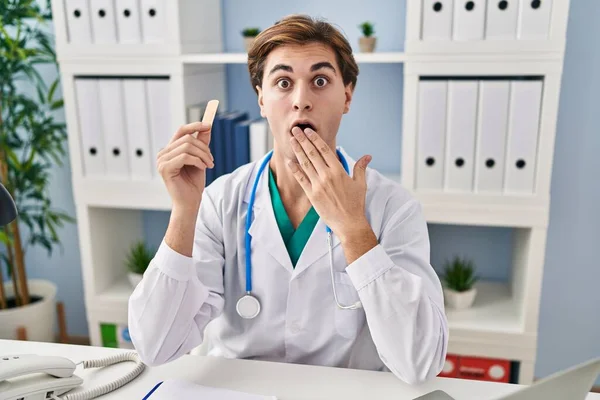 Young Doctor Man Holding Band Aid Covering Mouth Hand Shocked — Stock Photo, Image