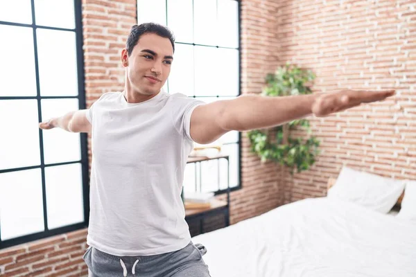 Genç İspanyol adam gülümseyerek yatak odasında kendine güvenen yoga eğitimi alıyor.
