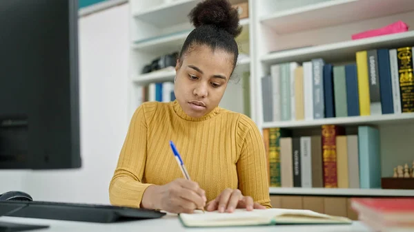 図書館でノートを取るコンピュータを使用して若いアフリカ系アメリカ人女性の学生 — ストック写真