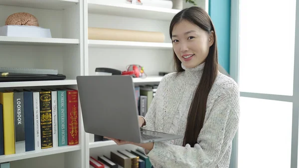 Young chinese woman student using laptop studying at library university