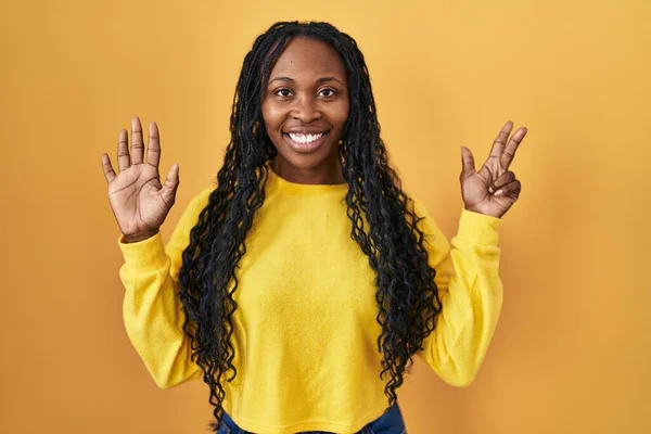 Африканская Женщина Стоящая Желтом Фоне Показывающая Пальцами Номер Восемь Улыбаясь — стоковое фото