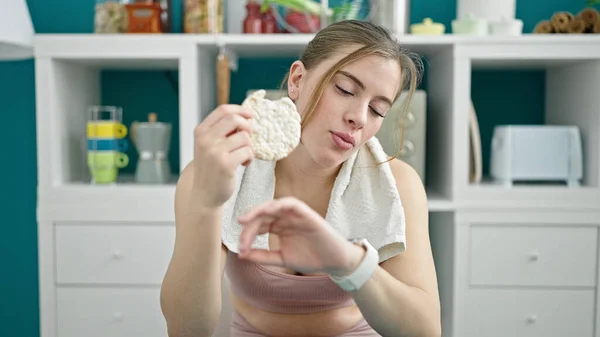 Junge Blonde Frau Sportkleidung Isst Reiskuchen Und Schaut Stoppuhr Auf — Stockfoto