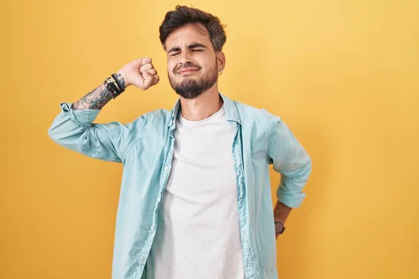 Nuori Latinomies Jolla Tatuoinnit Keltaisen Taustan Päällä Venyttely Takana Väsynyt — kuvapankkivalokuva