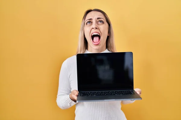Młoda Blondynka Trzyma Laptopa Wściekła Wściekła Krzycząc Sfrustrowana Wściekła Krzycząc — Zdjęcie stockowe