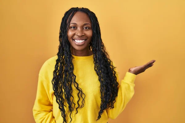 Африканська Жінка Стоїть Над Жовтим Фоном Посміхаючись Радісно Презентує Вказує — стокове фото