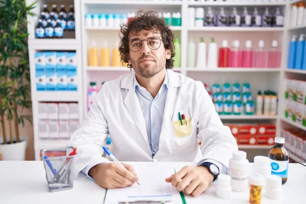 Joven Hispano Trabajando Farmacia Relajado Con Expresión Seria Cara Simple —  Fotos de Stock