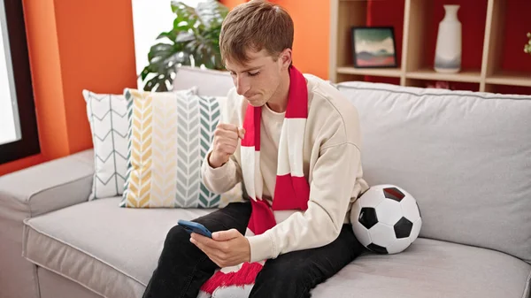 Mladý Kavkazský Muž Podporující Fotbalový Tým Pomocí Smartphonu Doma — Stock fotografie