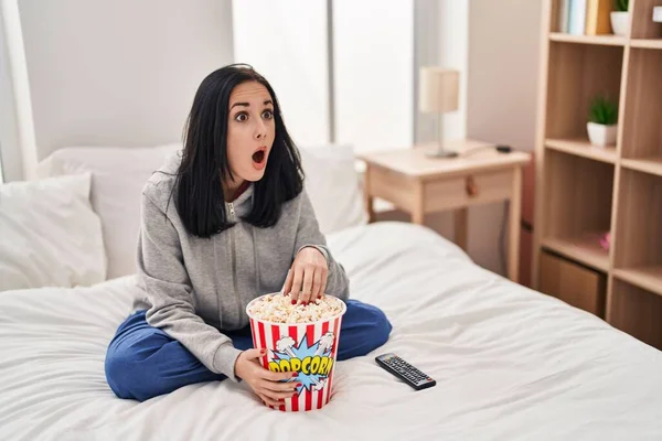 Hispanic Woman Eating Popcorn Watching Movie Bed Afraid Shocked Surprise — Stock Photo, Image