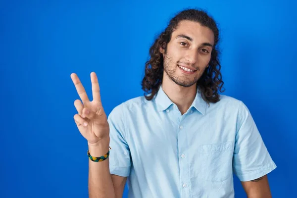 Joven Hombre Hispano Pie Sobre Fondo Azul Sonriendo Mirando Cámara —  Fotos de Stock